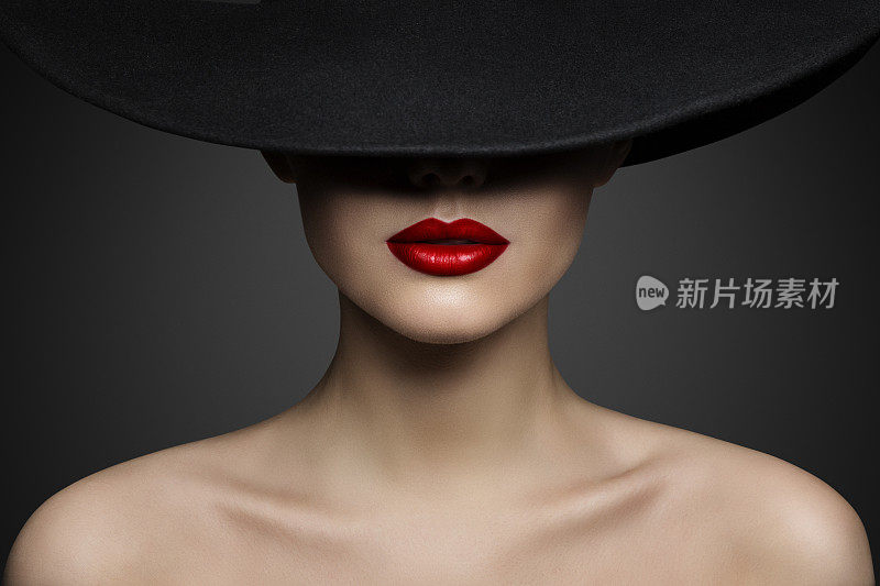 红唇化妆特写。神秘的时尚女人的脸隐藏在黑色帽檐帽。优雅的复古女士Fine Art肖像在灰色背景